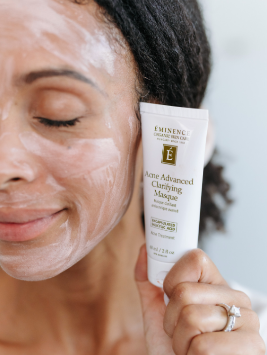 Person applying Eminence Acne Advanced Clarifying Masque to their face.