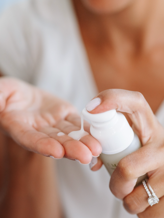 Person applying cream from a small container to their hand